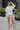 Frontal view of the Where To Next Top that features a soft cream material, a round neckline, a long cuffed sleeve, two side slits, and a thick bottom hem.
