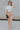 Full body front view of model wearing the Now And Forever Top that has ivory textured fabric, a cropped waist, lettuce trim, a high neckline and short sleeves