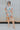 Full body view of model wearing the Dreamy Floral Romper which features white, red, tan, sage, pink, muted yellow and blue cotton fabric, floral pattern, folded hem, two side pockets, two back pockets, button snap closure, two front chest pockets, collare
