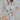 Front view of model wearing the Dreamy Floral Romper which features white, red, tan, sage, pink, muted yellow and blue cotton fabric, floral pattern, folded hem, two side pockets, two back pockets, button snap closure, two front chest pockets, collared ne
