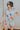 Front view of model wearing the Dreamy Floral Romper which features white, red, tan, sage, pink, muted yellow and blue cotton fabric, floral pattern, folded hem, two side pockets, two back pockets, button snap closure, two front chest pockets, collared ne