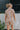 Back view of model wearing the Floral Haze Romper that has white denim fabric with a floral pattern, folded hems, pockets, snap closures, a collared neckline, and short sleeves