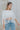 Front view of model wearing the Anywhere With You Top which features off white knit fabric, cropped waist, tassel hem details, open knit details, round neckline with monochrome stitch details and short sleeves with tassel hem details.