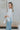 Side view of model wearing the Anywhere With You Top which features off white knit fabric, cropped waist, tassel hem details, open knit details, round neckline with monochrome stitch details and short sleeves with tassel hem details.