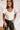Frontal view of the Game-On Bodysuit that features a white ribbed material, a V neckline, a ruffled short sleeve, and a thong bottom with a snap closure.