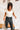 Frontal view of the Game-On Bodysuit that features a white ribbed material, a V neckline, a ruffled short sleeve, and a thong bottom with a snap closure.
