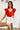 Frontal view of the Game-On Bodysuit that features a red ribbed material, a V neckline, a ruffled short sleeve, and a thong bottom with a snap closure.