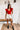 Frontal view of the Game-On Bodysuit that features a red ribbed material, a V neckline, a ruffled short sleeve, and a thong bottom with a snap closure.