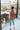 Full body back view of model wearing the Roam Free Cardigan, which features terracotta knit fabric with a blush floral print, a button-up front with a collar and brown tortoise buttons, two chest pockets, and long sleeves. 