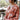 Side view of model wearing the Roam Free Cardigan, which features terracotta knit fabric with a blush floral print, a button-up front with a collar and brown tortoise buttons, two chest pockets, and long sleeves. Cardigan is worn half buttoned