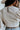 Back view of model wearing The Right Cord Top features lightweight cream-colored corduroy, a round neckline, 3/4 sleeves with elastic wrists, a keyhole button back, and a back zipper