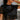 Close-up front view of model wearing the Night Out Sequin Top, which features a sheer black sequin material, a round neck, short sleeves, a black liner, and a back zipper closure