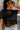 Close-up front view of model wearing the Night Out Sequin Top, which features a sheer black sequin material, a round neck, short sleeves, a black liner, and a back zipper closure