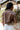 Back view of model wearing the Yellowstone Cropped Denim Jacket features brown denim, a collared neckline with draped lapels, two side slit pockets, long sleeves, and a cropped fit.