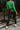 Back view of model wearing The Lucky Me Sweater features a green knit material, a scoop neck, long sleeves, ruffle detailing at the front sides, and a thick bottom hem.