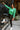 Front view of model wearing The Lucky Me Sweater features a green knit material, a scoop neck, long sleeves, ruffle detailing at the front sides, and a thick bottom hem.