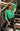 Front view of model wearing The Lucky Me Sweater features a green knit material, a scoop neck, long sleeves, ruffle detailing at the front sides, and a thick bottom hem.