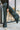 Front view of model wearing The Get In The Groove Pants  features textured dark green fabric with navy stripes, an elastic waist, wide flowy legs, and ankle slits.