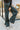 Front view of model wearing The Get In The Groove Pants  features textured dark green fabric with navy stripes, an elastic waist, wide flowy legs, and ankle slits.