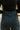 Back view of model wearing The Get In The Groove Pants  features textured dark green fabric with navy stripes, an elastic waist, wide flowy legs, and ankle slits.