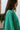 Side view of model wearing The Best Of Luck Sweatshirt In Green features knit fabric with terrycloth paneling, long raglan sleeves, raw hem details, and a high-low hemline with side slits