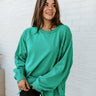 Front view of model wearing The Best Of Luck Sweatshirt In Green features knit fabric with terrycloth paneling, long raglan sleeves, raw hem details, and a high-low hemline with side slits