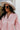Close-up front view of model wearing the All My Love Faux-Leather Top, which features a pink faux-leather material, a collar neck, a V neckline, long cuffed sleeves, a curved bottom hem, and an oversized fit.