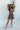 Full body front view of model wearing the I Like Your Vibe Floral Dress, which features a brown chiffon material, a taupe floral print, a curved neckline, long sleeves, a tier design with ruffles, a smocked back, and a mini length