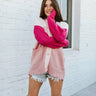 Front view of model wearing the Forever Yours Cardigan, which features a pink colored knit material, a monochromatic design, a V neckline, a button-up front, long sleeves, two front pockets, and an oversized fit