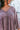 Close-up front  view of model wearing the Long Time Coming Dress, which features washed purple fabric, three-quarter sleeves with elastic wrists, a v-neckline, and a flowy tiered body