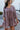 Front view of model wearing the Long Time Coming Dress, which features washed purple fabric, three-quarter sleeves with elastic wrists, a v-neckline, and a flowy tiered body