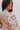 Close-up shoulder view of model wearing the In The Groove Top, which features a blue, pink, orange, and yellow floral print, long balloon sleeves with elastic trim , a square neckline, and a flowy babydoll fit