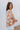 Side view of model wearing the In The Groove Top, which features a blue, pink, orange, and yellow floral print, long balloon sleeves with elastic trim , a square neckline, and a flowy babydoll fit