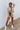 Full body front view of model wearing the Get Cozy Top, which features a sand-colored knit material, a collar neck, a 3/4 button-up front, long sleeves, and a loose fit. Tucked into matching shorts.