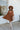 Full body front view of model wearing the Spice It Up Dress, which features camel-colored fabric, a v-neckline with a cutout, a v-back with a tie, half sleeves, and a flowy fit