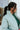 Side view of model wearing the Breckenridge Jacket, which features a green colored material, a stitched quilt design, a high neck, long sleeves with a cinching at the wrist, two front pockets, and a front zipper closure