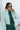 Front view of model wearing the Breckenridge Jacket, which features a green colored material, a stitched quilt design, a high neck, long sleeves with a cinching at the wrist, two front pockets, and a front zipper closure