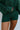 Close-up front view of model wearing the Headed North Shorts, which feature hunter green fabric with horizontal stitched stripes and an elastic waist