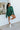 Full body front view of model wearing the Headed North Shorts, which feature hunter green fabric with horizontal stitched stripes and an elastic waist