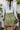Close-up back view of model wearing the Feeling Lucky Skirt, whcih features green silk fabric with a green lining, a pleated waistband with a smocked back, a front zipper detail, and two front flap pockets