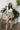 Full body front view of model wearing the Feeling Lucky Skirt, whcih features green silk fabric with a green lining, a pleated waistband with a smocked back, a front zipper detail, and two front flap pockets