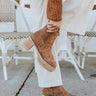 Side view image of model's shoes- model is wearing the Aubrey Boots, which feature camel faux-leather, side zippers, and brown stacked block heels.