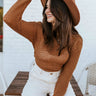 Front view of model wearing the West Coast Sweater, which features open-knit fabric, a round rolled-hem neckline, long sleeves with ribbed elastic wrists, and a cropped back with a tie at the hemline