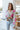 Front view of the Full Bloom Cardigan, which features a grey colored knit material, a multi-colored floral pattern, a V neckline, a button-up front, and long sleeves. Cardigan is styled with front tuck.