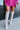 Close-up front view of model wearing the Stephanie Boot in Taupe, which is a tall white boot featuring a taupe faux leather, a 3" stacked heel, a pointed toe, and pull-on tabs. 