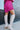 Close-up side view of model wearing the Stephanie Boot in Taupe, which is a tall white boot featuring a taupe faux leather, a 3" stacked heel, a pointed toe, and pull-on tabs. 
