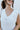 Close-up front view of model wearing the Aspen Sweater Vest, which features ribbed knit ivory fabric, a v-neckline, and a slight high-low hemline with side slits. Vest is styled tucked up.