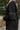 Side view of model wearing The Call Me Rhinestone Fringe Dress which features black sweatshirt material, rhinestone fringe across the back and sleeves, a round neckline, and long sleeves with ribbed cuffs.