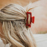 Side view of model wearing the the Harper Hair Clip in Cranberry, which is a dark red rectangular plastic clip with claw teeth.