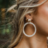 Close up image of model wearing the Upper East Side Earring, which features gold circles on post backs with large circular white beaded pendants.